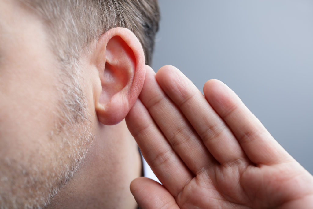 A man with his hand on his ear to listen better