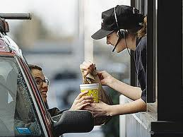 A Woman Handing a Cup from a Drive Through Window